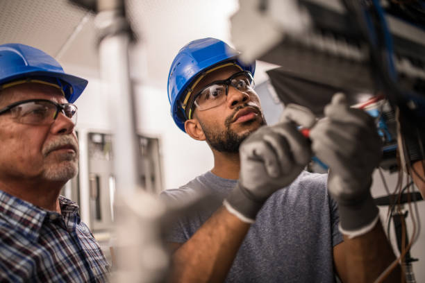Electricians working on a fuse box Photo of a senior caucasian and young African-American electrician working on a fuse box. electrician photos stock pictures, royalty-free photos & images
