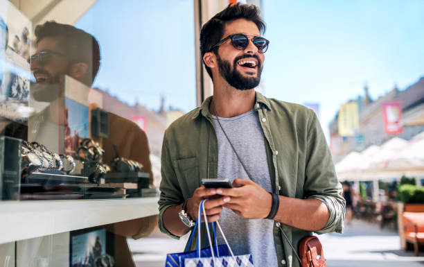 Young man in shopping looking for presents. Consumerism, fashion, lifestyle concept Modern young man enjoying in shopping. Consumerism, fashion, lifestyle concept shopping bag photos stock pictures, royalty-free photos & images
