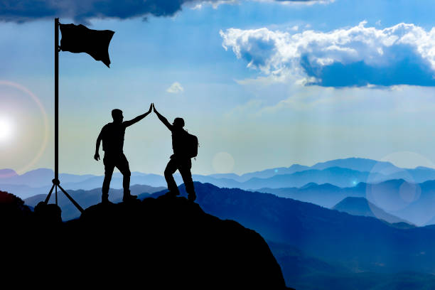 reaching the goal and celebrating success - leadership risk cliff mountain climbing imagens e fotografias de stock