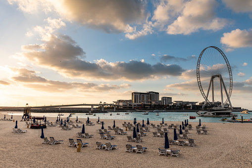 Empty JBR Beach at Dubai Marina and the island Blue Waters with the unfinished Ferris wheel in the evening
