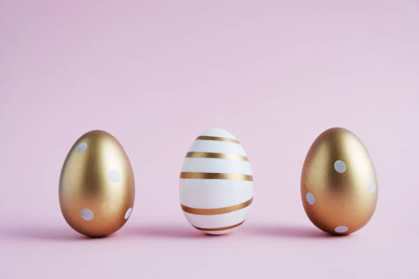 istock Three Easter eggs painted with gold paint in different patterns stand on a pink pastel color. Easter concept. Horizontal orientation. Copy space 1214564971