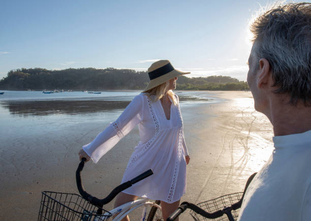 istock Mature couple ride bikes down beach at sunrise 1214565146