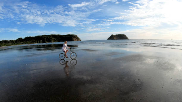 istock Woman rides bicycle down beach at sunrise 1214565212