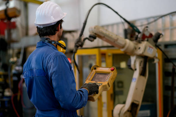 istock Back of blue uniform technician or worker man control and check the robot working in factory 1214565220