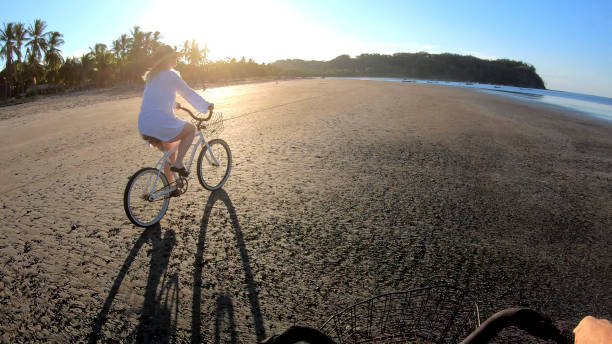 istock Mature couple ride bikes down beach at sunrise 1214567156
