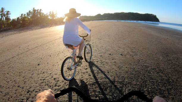 istock Mature couple ride bikes down beach at sunrise 1214567158