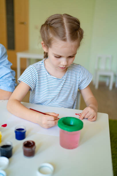 istock small girl drawing with brush and paints 1214568462