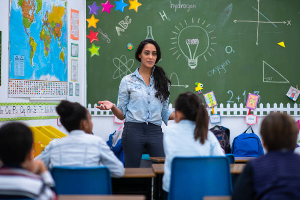 istock Young Female Elementary Teacher Instructs in Class stock photo 1214570071