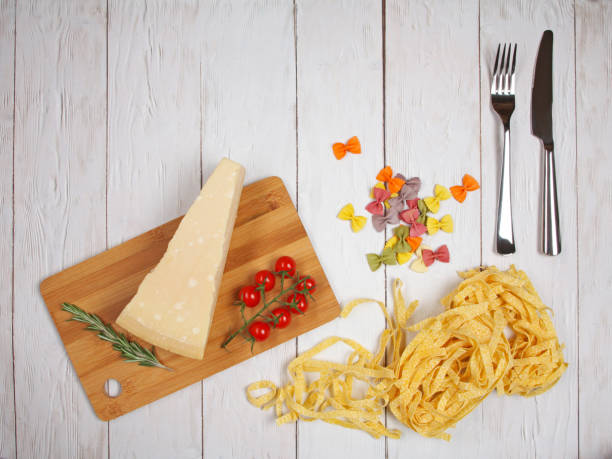 suchy włoski makaron fettuccini i farfalle z pomidorami, serem, rozmarynem, widelcem i nożem - bow tie pasta italian cuisine bow heap zdjęcia i obrazy z banku zdjęć
