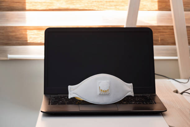 istock Black notebook with protecting mask on the table. Coronavirus concept. Work from home concept 1214572118