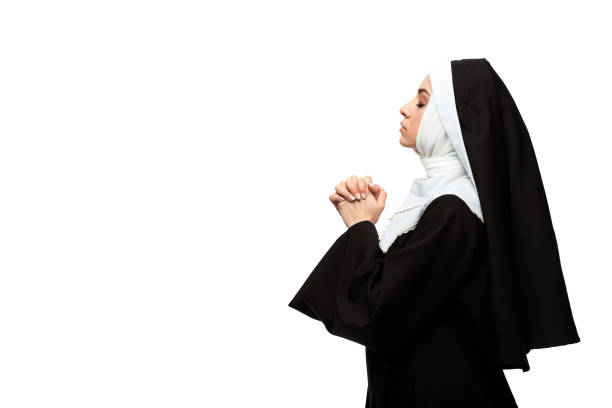 istock attractive nun praying with closed eyes and hands together isolated on white 1214572424