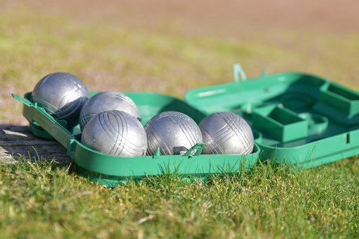 Petanque balls in a green box on the grass