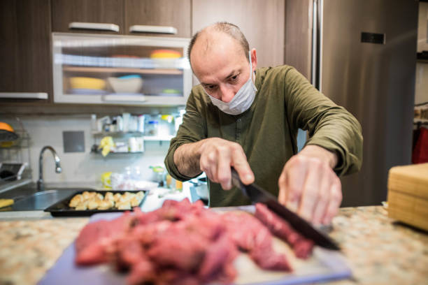 Man is cooking whit mask while covid 19 stock photo