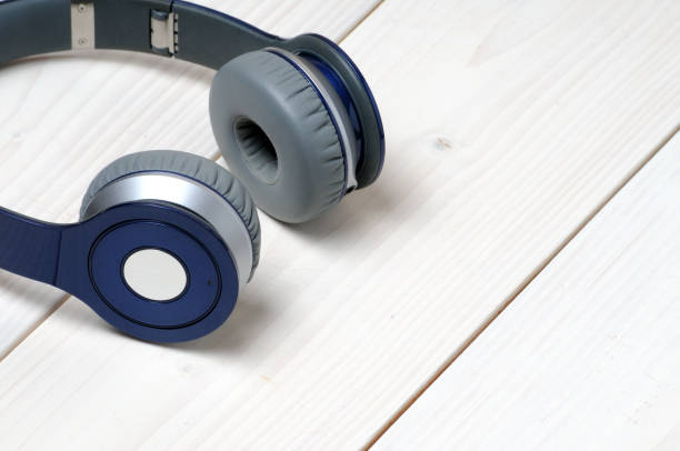 istock Blue and silver modern headphones on a white wooden background 1214588913