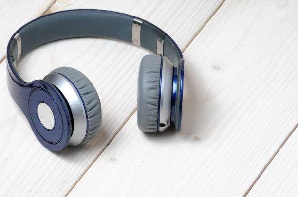 istock Blue and silver modern headphones on a white wooden background 1214588916