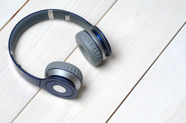 istock Blue and silver modern headphones on a white wooden background 1214588988