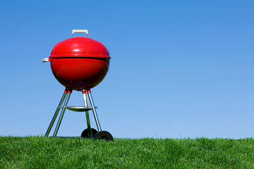 Red Generic Brand Barbecue Grill against a Blue Sky with Four Legs
