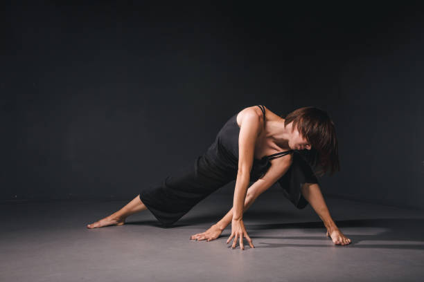 portrait of a beautiful woman dancing on black background. ballet and contemporary dancer dancing on dark backdrop. contemporary art. plastic and flexible girl in black clothes posing on a black wall - modern dancing imagens e fotografias de stock