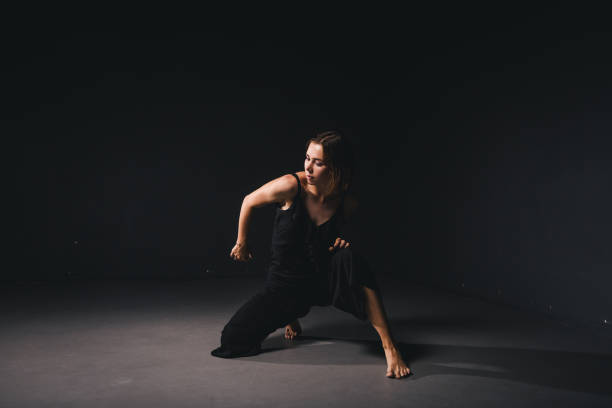 portrait of a beautiful woman dancing on black background. ballet and contemporary dancer dancing on dark backdrop. contemporary art. plastic and flexible girl in black clothes posing on a black wall - modern dancing imagens e fotografias de stock