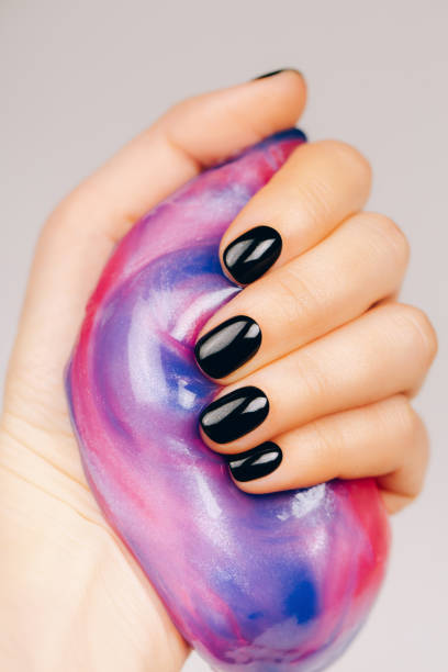 istock hands with black manicure holding slime 1214592927