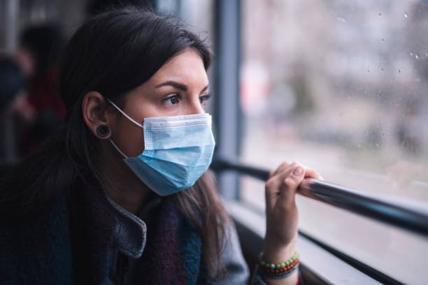 istock Worried Woman With Protective Face Mask Looking Through Window. 1214592992