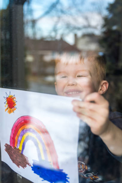 istock Young Boy sticking his drawing on home window during the Covid-19 crisis 1214595904