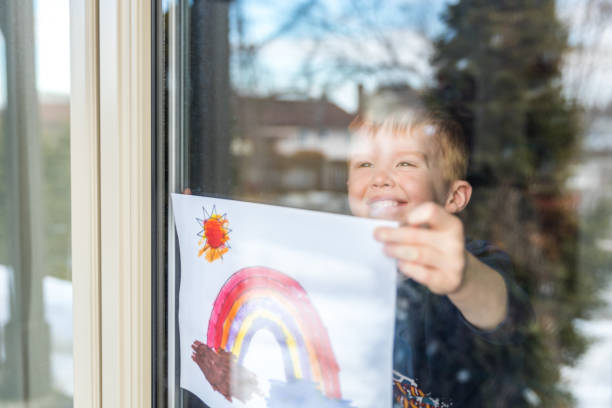 istock Young Boy sticking his drawing on home window during the Covid-19 crisis 1214595943