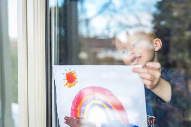 istock Young Boy sticking his drawing on home window during the Covid-19 crisis 1214595964