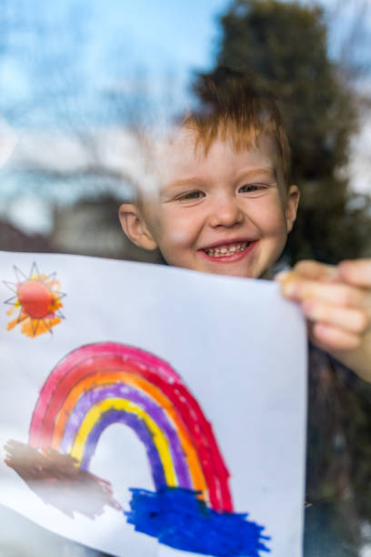 istock Young Boy sticking his drawing on home window during the Covid-19 crisis 1214595986