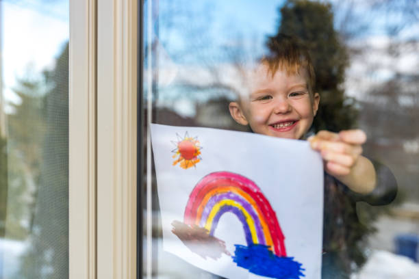istock Young Boy sticking his drawing on home window during the Covid-19 crisis 1214595998
