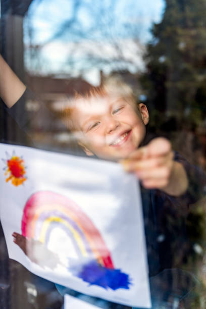 istock Young Boy sticking his drawing on home window during the Covid-19 crisis 1214596014