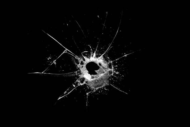 istock hole in the glass with cracks isolated on a black background 1214602653