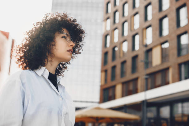 istock Caucasian businesswoman is posing against a building while looking attentive through eyeglasses 1214615156