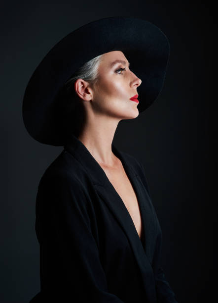 Studio shot of a beautiful mature woman wearing a hat and posing against a dark background