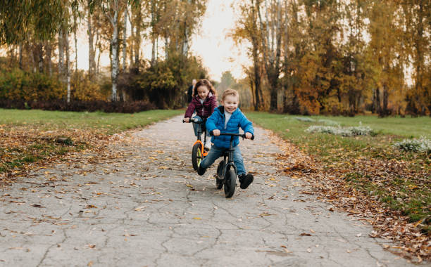 istock Charming caucasian siblings are having fun during an autumn walk in the park while riding their bikes 1214619875