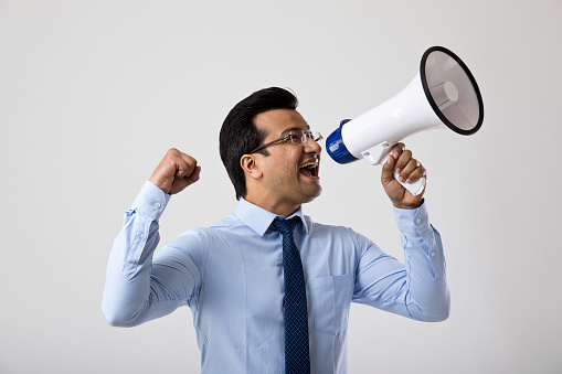 Excited businessman cheering and screaming through megaphone