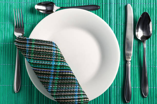 table setting Cutlery and a white plate on a green close up