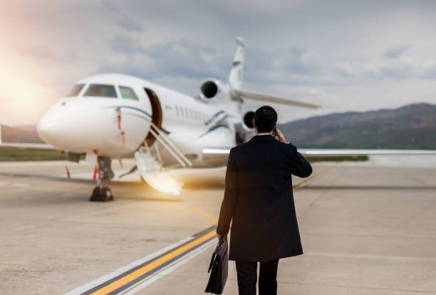 achtermening van zakenman die naar privé vliegtuig loopt - baggage fotos stockfoto's en -beelden
