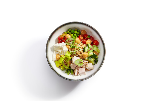 Couscous with chiken and avocado top view. Poke bowl of fresh vegetables and tofu cheese. Delicious meal with cut cucumber and tomato. Traditional dish decorated with sauce and pepper.