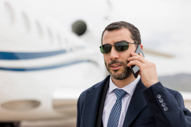 istock Businessman making phone call in front of private jet 1214625140