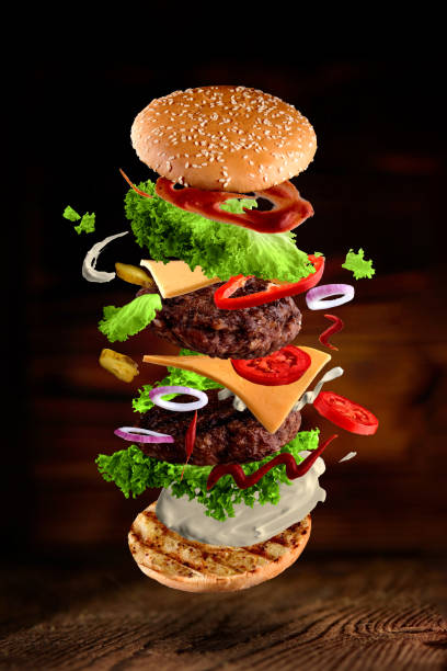 istock Maxi hamburger, double cheeseburger with flying ingredients isolated on wooden background. High resolution image 1214626294