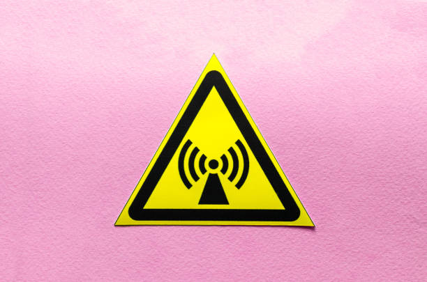 yellow warning sign electromagnetic field on a pink background close up