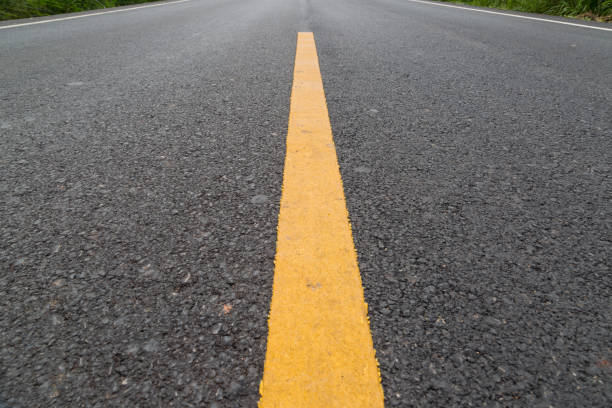 istock The yellow line on the road with tree and sky 1214627044