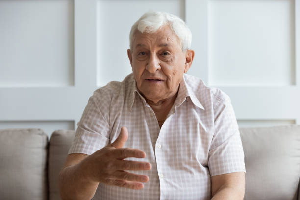 Head shot serious older man looking at camera and talking