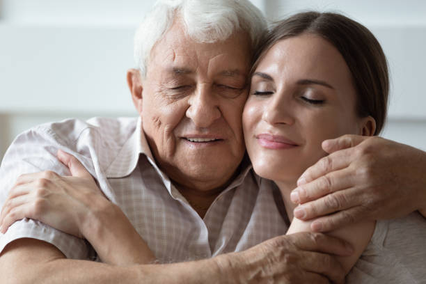 happy adult daughter and older father hugging with closed eyes - aging process middle women men imagens e fotografias de stock