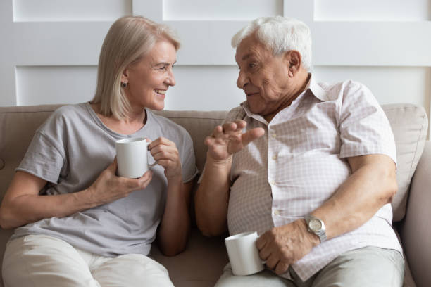 glückliche ältere frau und ehemann im gespräch, trinken heiße getränke - aging process middle women men stock-fotos und bilder