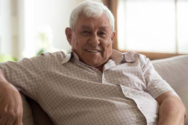 istock Head shot portrait smiling older man sitting on couch 1214631519