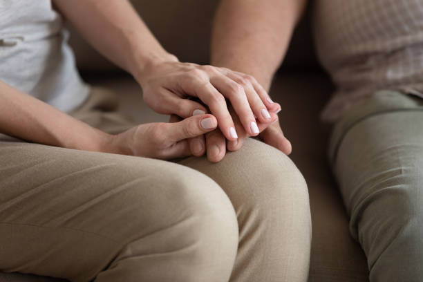 istock Middle-aged woman holding older man hands, expressing support 1214631538