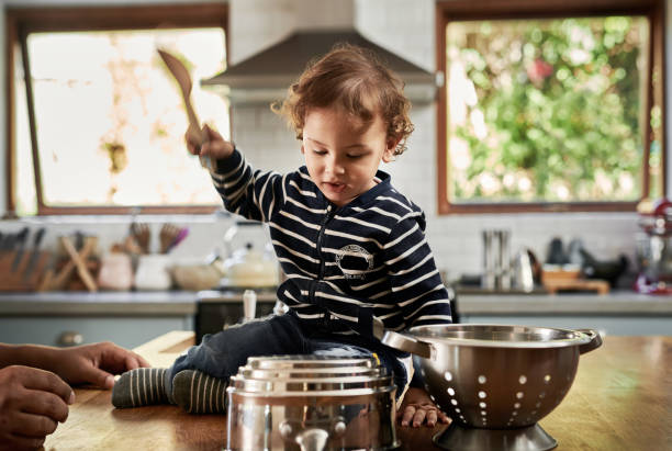 We have a drummer in the making Shot of an adorable little boy playing with pots and pans in the kitchen at home toddler hitting stock pictures, royalty-free photos & images