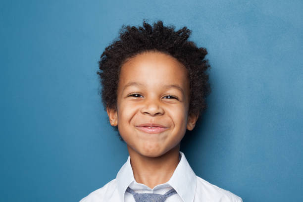 istock American black child boy smiling and looking at camera on blue background 1214636929
